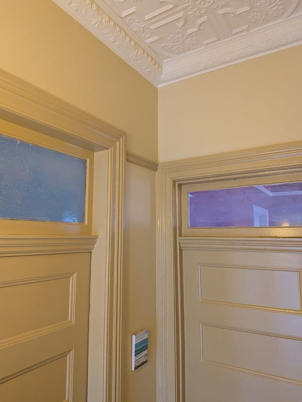 The same panelled doors after painting — smooth cream gloss finish beneath a crisp white ornate cornice