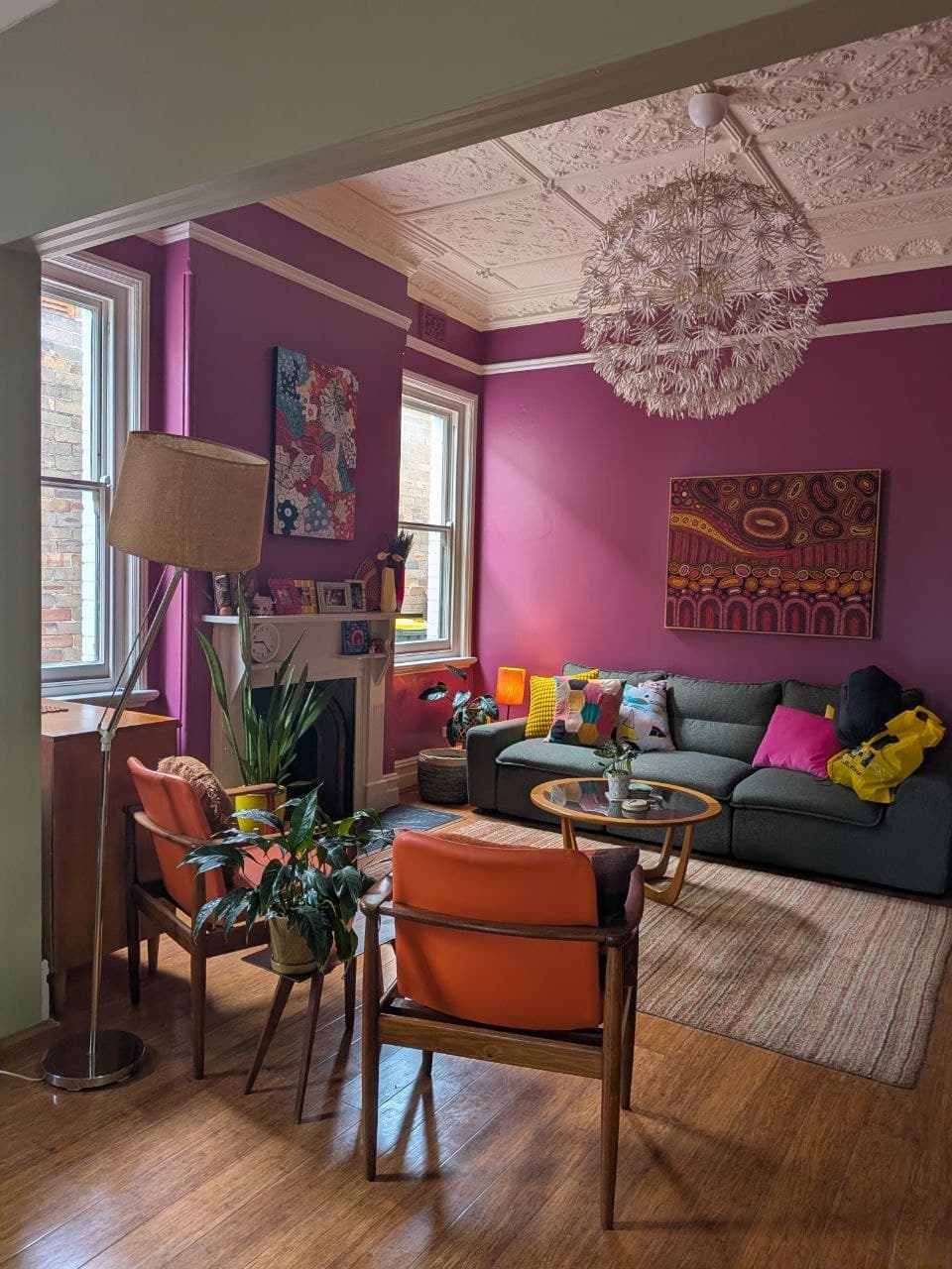 The finished living room — deep magenta feature walls, restored white pressed-tin ceiling and styled furnishings