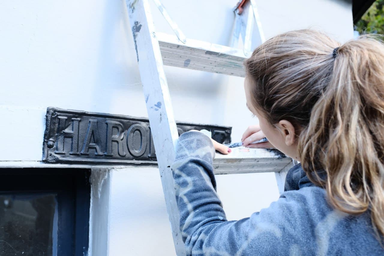 Painter working on exterior signage detail — precision and care in every brushstroke