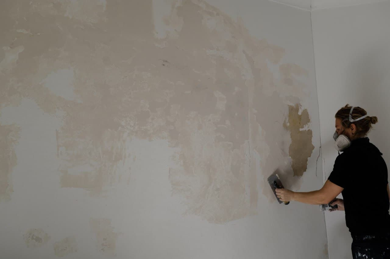 Painter carefully preparing a wall surface before painting